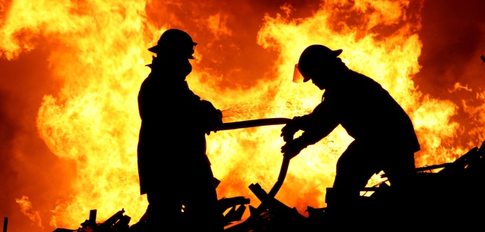 Eliminating Fire Damage Two fire fighters and flames