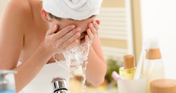 Woman splashing face with water in bathroom