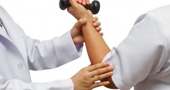 Doctor holding patient 's elbow for rehab weight training