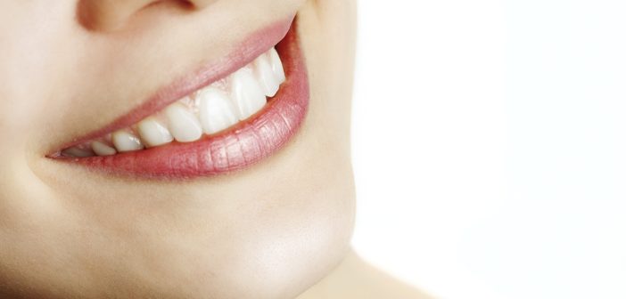 Fresh smile of woman with healthy teeth over white